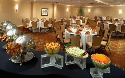 a banquet hall with white tables and chairs with flowers at Clinton Inn Hotel Tenafly in Tenafly