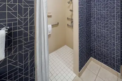 a bathroom with a shower with blue tiles at Homewood Suites by Hilton Newburgh-Stewart Airport in New Windsor