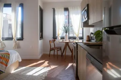 a kitchen with a table and a room with a bed at Billy Penn Studio at Kestrel Hotel in Philadelphia