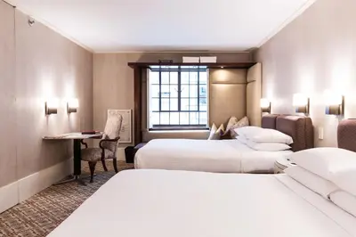 a hotel room with two beds and a desk at City Club Hotel in New York