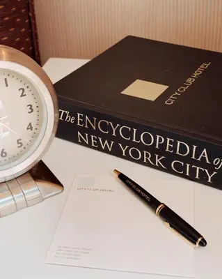 a book and a clock and a pen on a table at City Club Hotel in New York