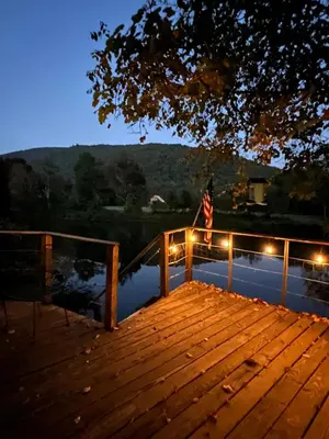 a wooden dock with an american flag and lights at A River Runs Through It in East Branch