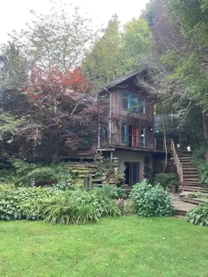 a large house with stairs leading up to it at A River Runs Through It in East Branch