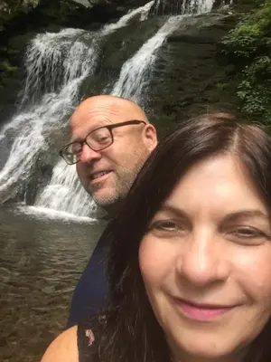 a man and a woman standing in front of a waterfall at Roscoe Cabin Pet friendly in Roscoe