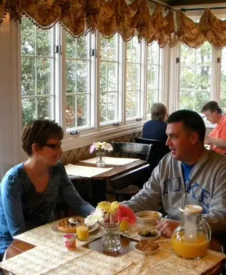 a man and woman sitting at a table eating food at Bird-in-Hand Village Inn & Suites in Bird in Hand