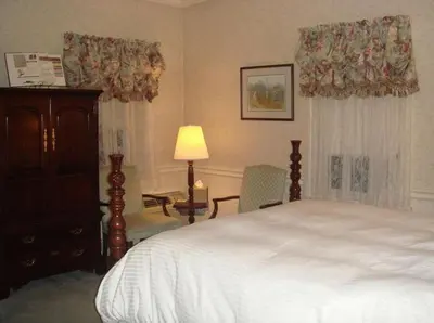 a bedroom with a bed and a dresser and a lamp at Bird-in-Hand Village Inn & Suites in Bird in Hand