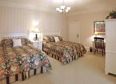 a bedroom with two beds and a table and a chair at Bird-in-Hand Village Inn & Suites in Bird in Hand
