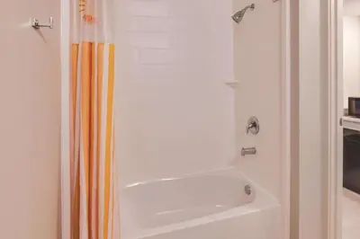 a bathroom with a shower with a white tub at La Quinta by Wyndham Philadelphia Airport in Essington