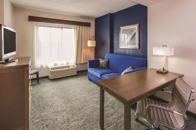 a hotel room with a blue couch and a table at La Quinta by Wyndham Philadelphia Airport in Essington
