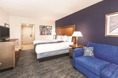 a hotel room with a bed and a blue couch at La Quinta by Wyndham Philadelphia Airport in Essington