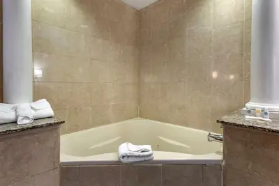 a bathroom with a bath tub with towels on the counter at Comfort Suites Newark - Harrison in Newark