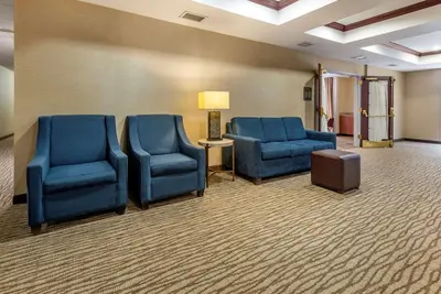 a waiting room with two blue chairs and a lamp at Comfort Suites Newark - Harrison in Newark