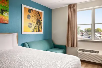 a bedroom with a bed and a chair next to a window at Days Inn by Wyndham Hershey in Hershey