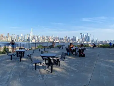 a group of tables and chairs with a view of a city at Cozy apt in WEST NY, NEW JERSEY, at 2 bloks from bus stop-15 minutes 2NY 7MINUTES VIA NYWATERWAY FERRY-BETTER CAN'T BE!! in West New York