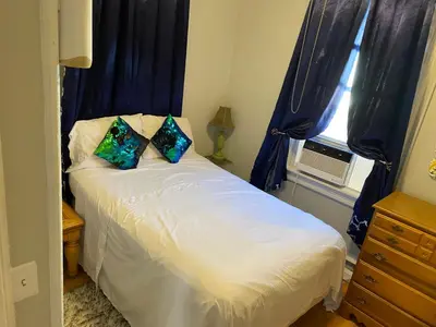 a bedroom with a bed with blue curtains and a window at Cozy apt in WEST NY, NEW JERSEY, at 2 bloks from bus stop-15 minutes 2NY 7MINUTES VIA NYWATERWAY FERRY-BETTER CAN'T BE!! in West New York