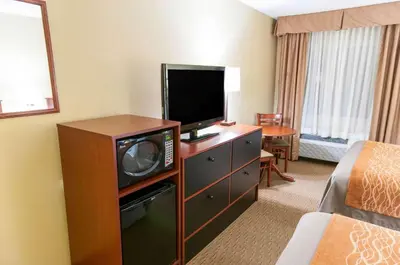 a hotel room with a flat screen tv and a bedroom at Comfort Inn New Holland Amish Country in New Holland