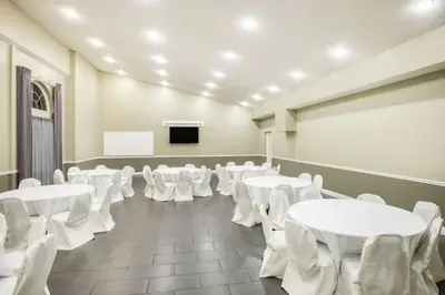 a room with white tables and chairs and a podium at Days Inn & Suites by Wyndham Cherry Hill - Philadelphia in Cherry Hill