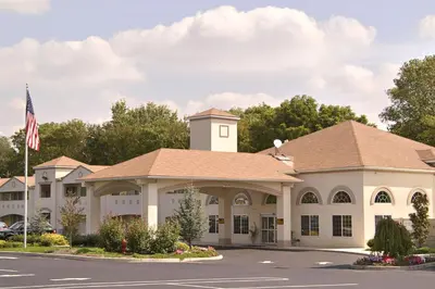 a large white building with a american flag at Days Inn & Suites by Wyndham Cherry Hill - Philadelphia in Cherry Hill