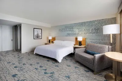 a hotel room with a bed and a chair at Sheraton Philadelphia Downtown in Philadelphia