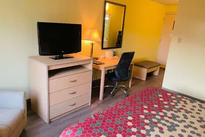 a bedroom with a desk with a television and a bed at Super 8 by Wyndham Gloucester in Gloucester City