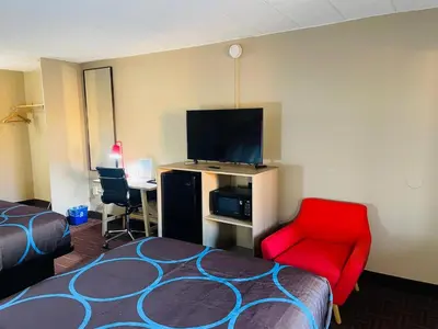 a hotel room with a bed and a red chair at Super 8 by Wyndham Gloucester in Gloucester City