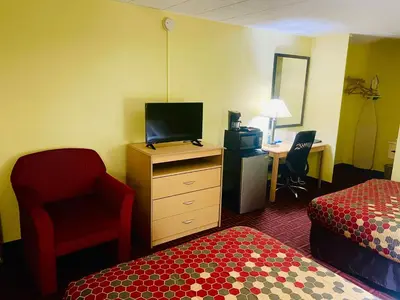 a hotel room with a bedroom with a bed and a desk at Super 8 by Wyndham Gloucester in Gloucester City
