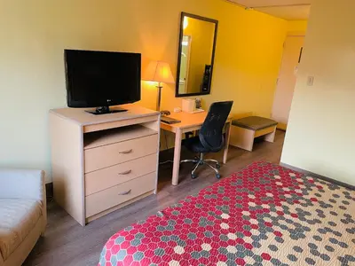 a hotel room with a bedroom with a desk and a television at Super 8 by Wyndham Gloucester in Gloucester City