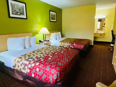 two beds in a hotel room with green walls at Super 8 by Wyndham Gloucester in Gloucester City