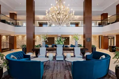 a large lobby with blue chairs and a table and a chandelier at The Westin Governor Morris, Morristown in Morristown
