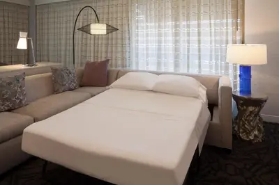 a living room with a couch and a white bed at The Westin Princeton at Forrestal Village in Princeton
