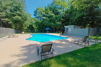 a swimming pool with three chairs in a yard at Quality Inn Spring Valley - Nanuet in Spring Valley