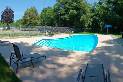 a swimming pool with two chairs and an umbrella at Quality Inn Spring Valley - Nanuet in Spring Valley