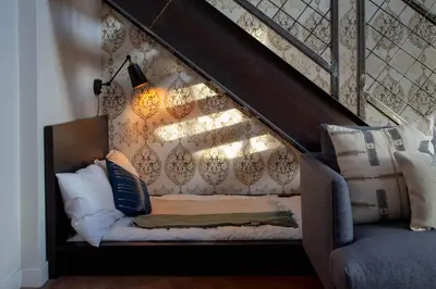 a couch with pillows on it under the stairs at Continental Congress Loft at Kestrel Hotel in Philadelphia