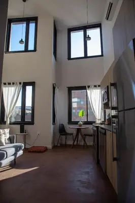 a living room with windows and a kitchen with a table at Continental Congress Loft at Kestrel Hotel in Philadelphia