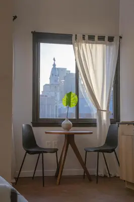 a table with a vase and two chairs in front of a window at Continental Congress Loft at Kestrel Hotel in Philadelphia