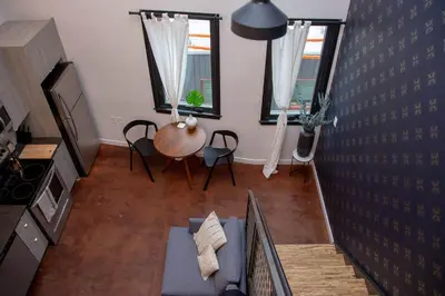 a living room with a couch and a table and two windows at Hive Room Loft at Kestrel Hotel in Philadelphia