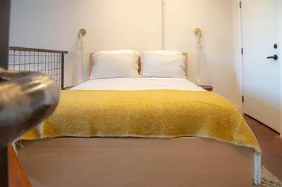 a bedroom with a bed with a yellow blanket on it at Mayor's Study Loft at Kestrel Hotel in Philadelphia