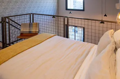 a bedroom with a large bed with white sheets at Mayor's Study Loft at Kestrel Hotel in Philadelphia