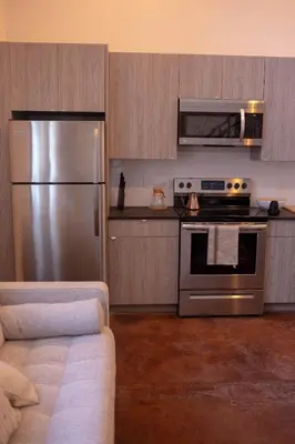 a kitchen with a stainless steel refrigerator and a couch at Mayor's Study Loft at Kestrel Hotel in Philadelphia