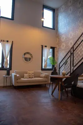 a living room with a couch and a table and windows at Viaduct Loft at Kestrel Hotel in Philadelphia