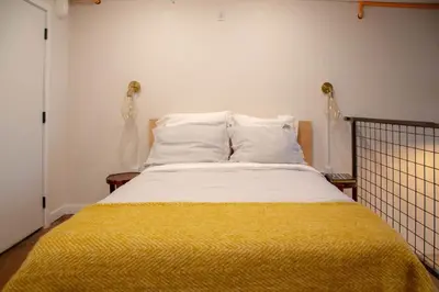 a bedroom with a bed with a yellow blanket on it at Viaduct Loft at Kestrel Hotel in Philadelphia