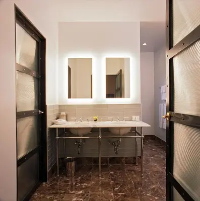 a bathroom with two sinks and two mirrors at Gild Hall, A Thompson Hotel, by Hyatt in New York