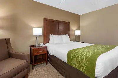 a hotel room with a large bed and a chair at Comfort Inn Edison - New Brunswick in Edison