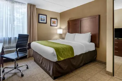 a hotel room with a bed and a desk and a chair at Comfort Inn Edison - New Brunswick in Edison