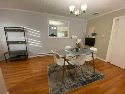 a dining room with a glass table and white chairs at A Modern Apt close to downtown in Lancaster