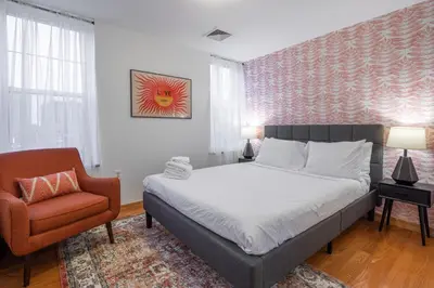 a bedroom with a bed and a chair at The Stairway Suites - Convention Center in Philadelphia