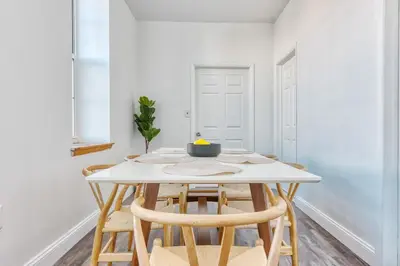 a white dining room with a white table and chairs at The Stairway Suites - Convention Center in Philadelphia