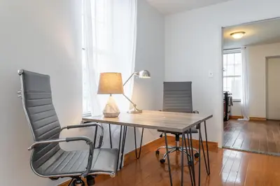 a desk with a lamp and two chairs in a room at The Stairway Suites - Convention Center in Philadelphia