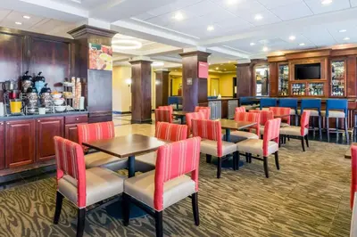 a restaurant with tables and chairs and a bar at Comfort Suites at Woodbridge in Avenel
