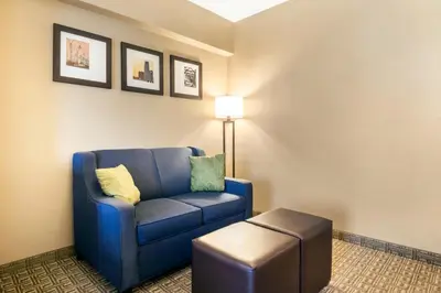 a living room with a blue chair and a stool at Comfort Suites at Woodbridge in Avenel